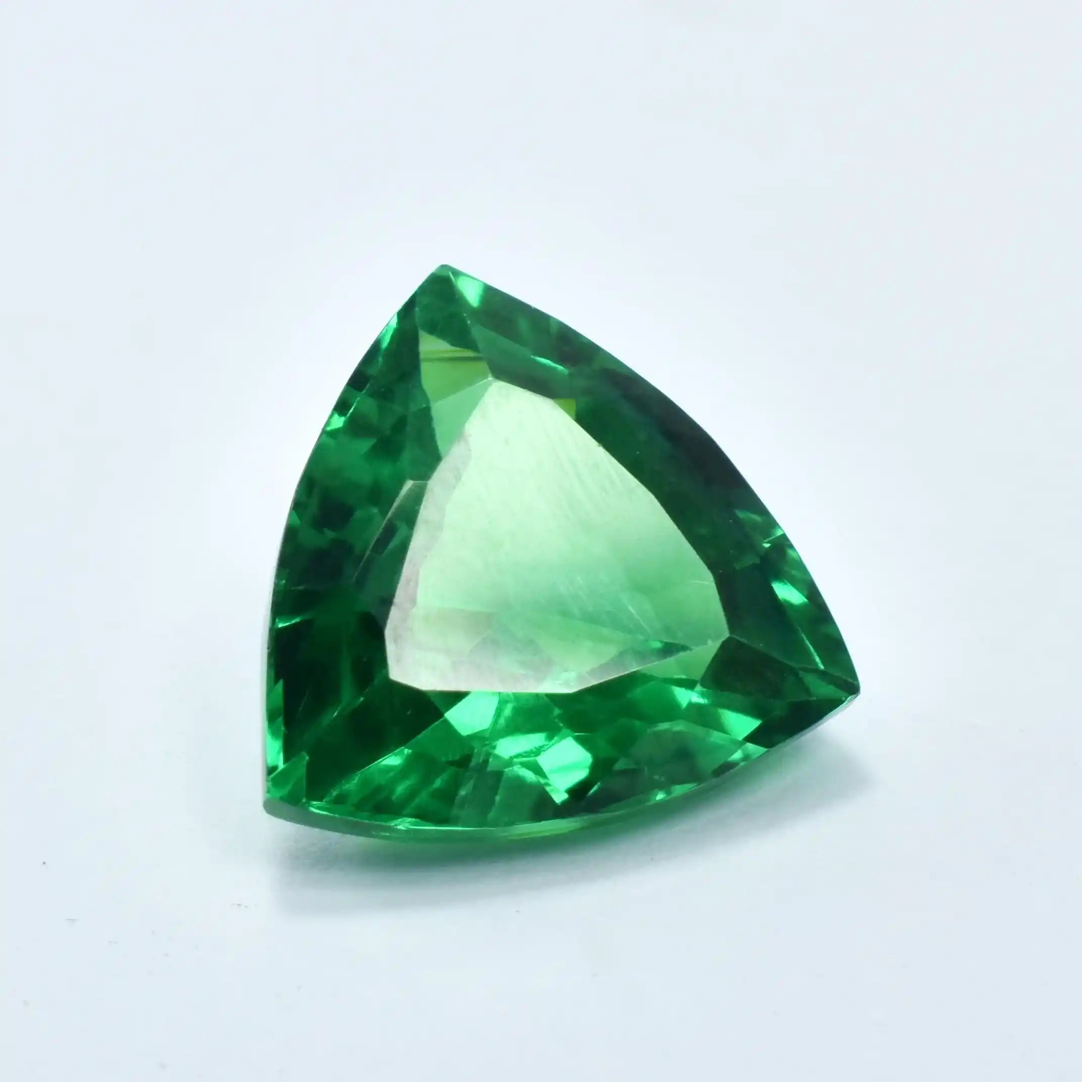 Trillion-cut green gemstone on a light gray background