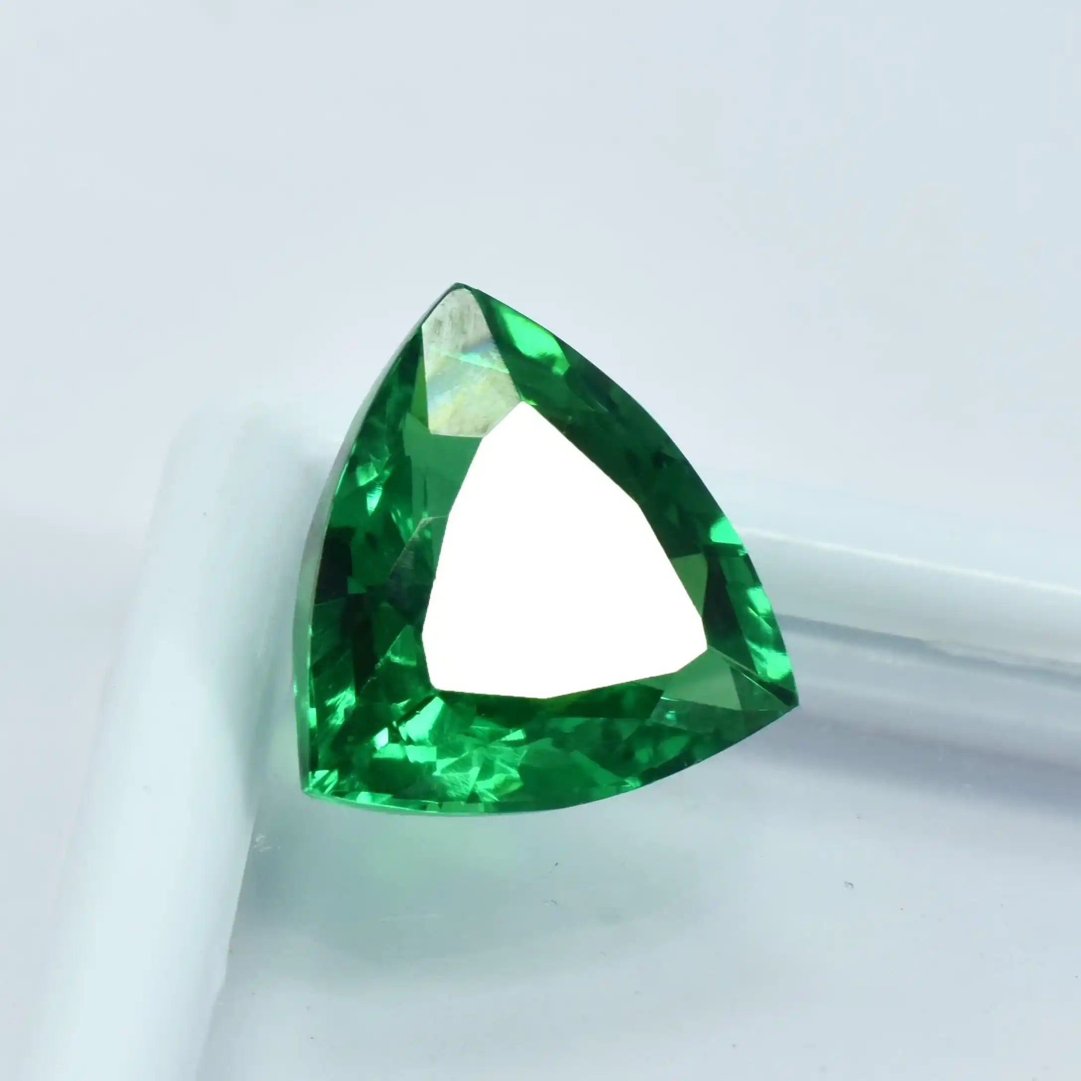 Triangular green gemstone on a white background