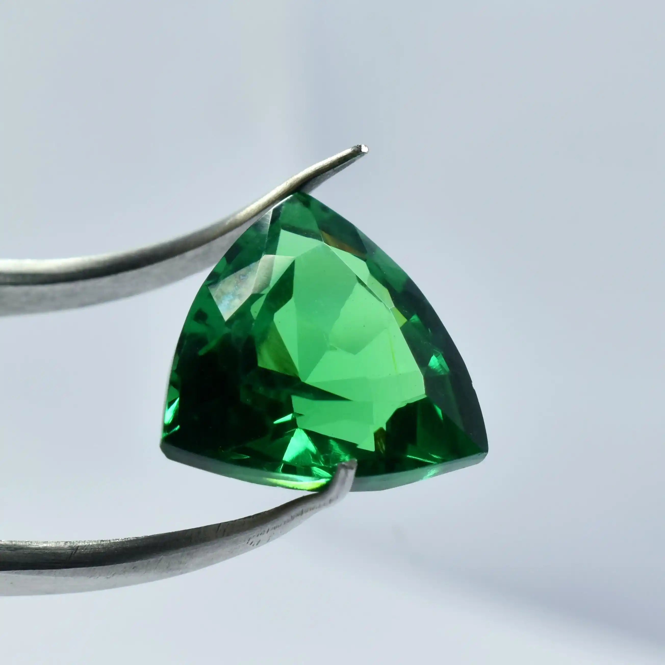Trillion-cut green gemstone on a white background