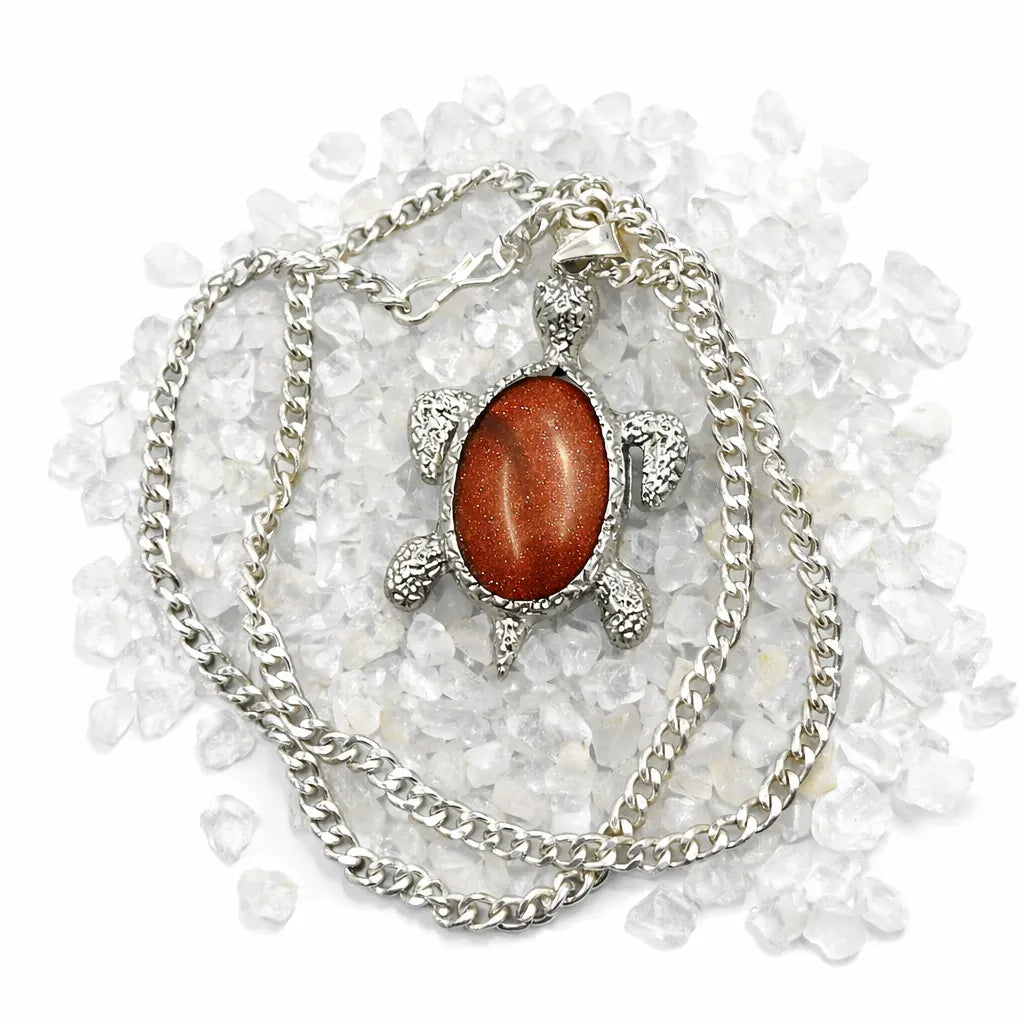 Necklace with a turtle pendant featuring a red stone on a white background
