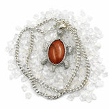 Necklace with a turtle pendant featuring a red stone on a white background
