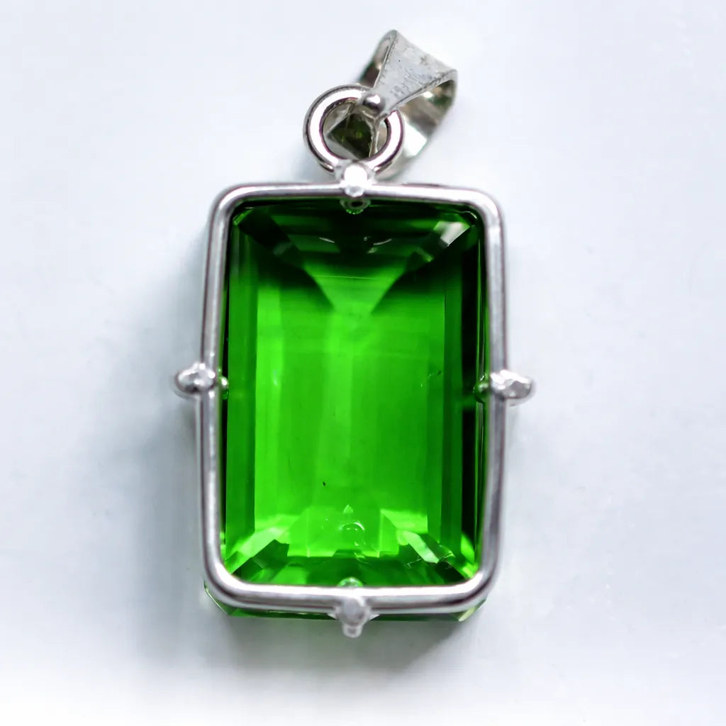Green gemstone pendant with silver frame on a white background