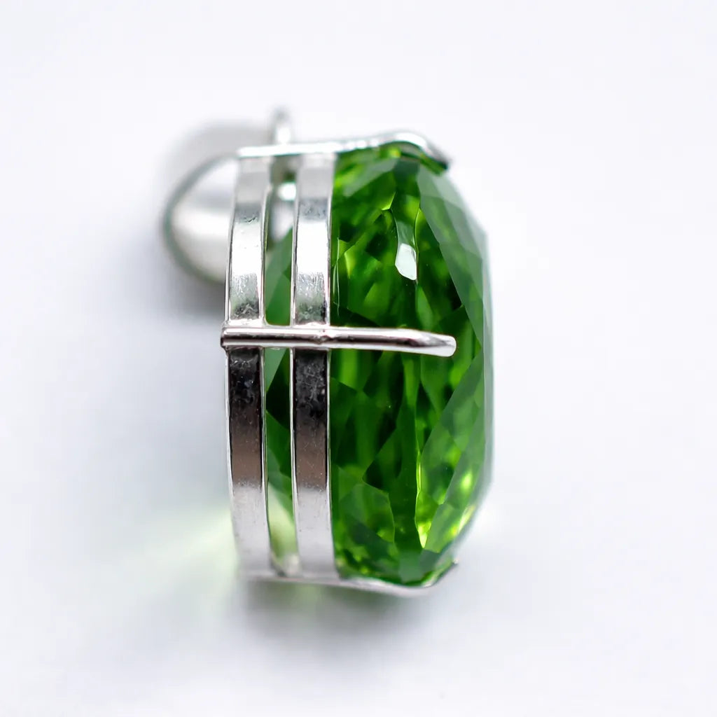 Green gemstone earring with silver setting on a white background