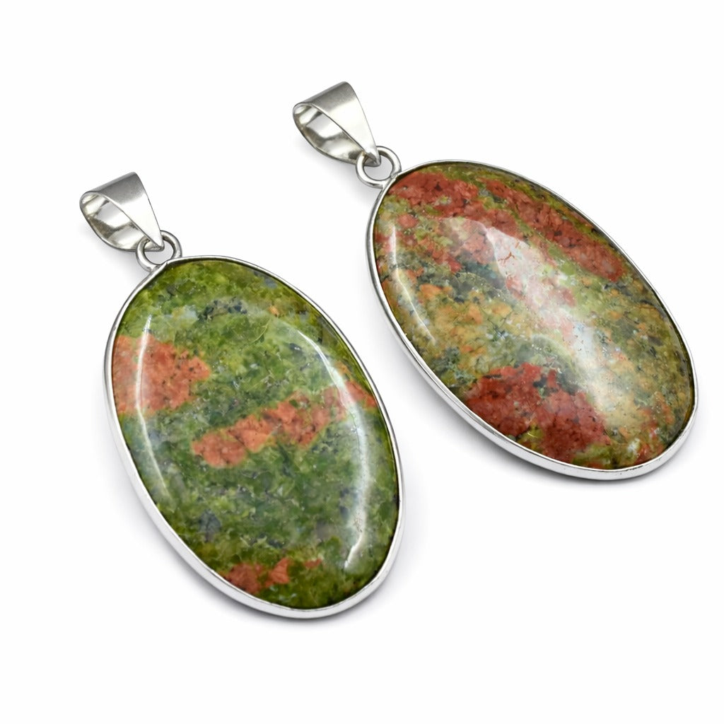 Two oval stone pendants with silver settings on a white background