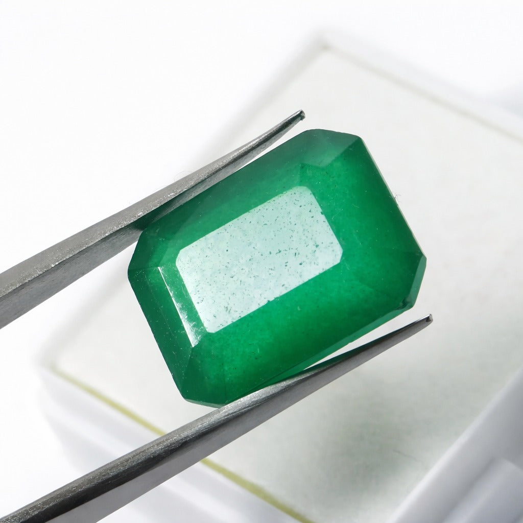 colombian emerald natural gemstone Faceted green gemstone held between tweezers on a white background